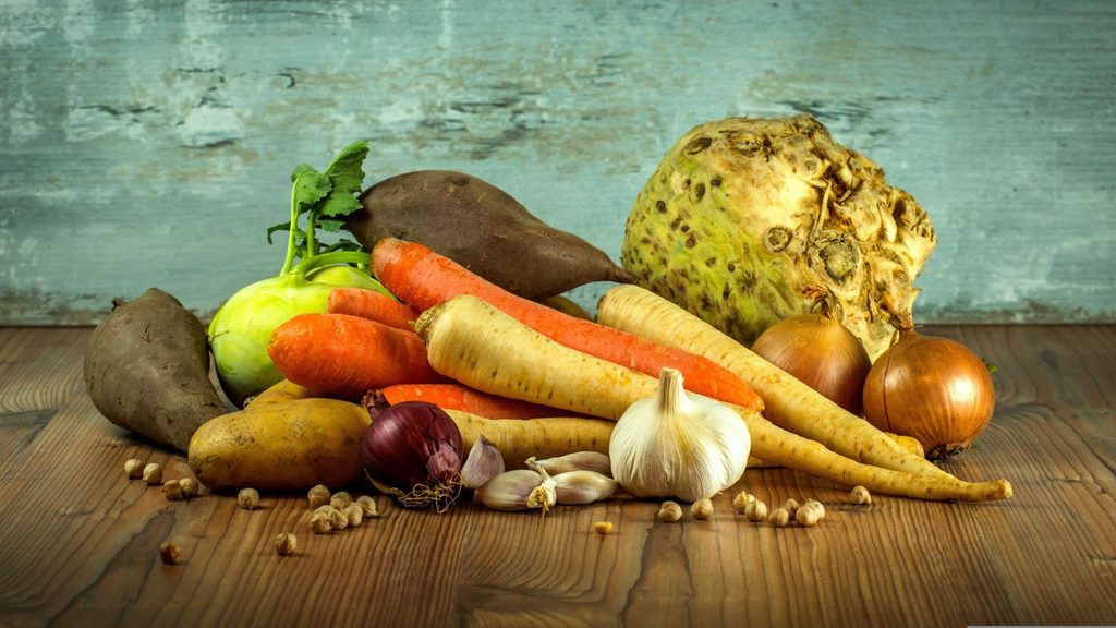 Чомлек: вкусът на Банско в едно гърне Зеленчуци върху дървен плот, сред които картофи, моркови, кромид лук, чесън и други.